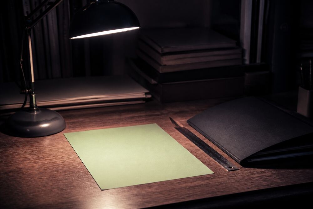 A flatbed editing desk in a dim room, a strip of 16mm film threaded through the gate and a small light box behind it, shot from slightly above at a three-quarter angle.